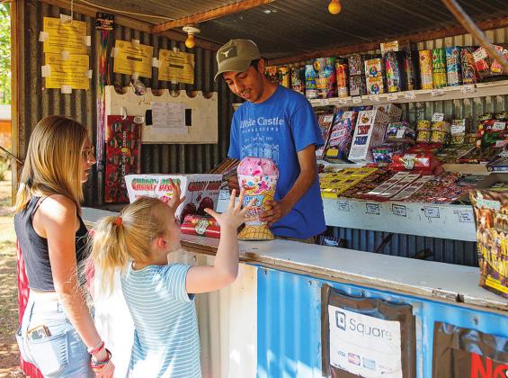 Drew Yanez helps pick out the perfect fireworks for Riley and Everleigh Hurt at the Marinez Family Fireworks stand located at 812 N. Cleveland in Rotan.